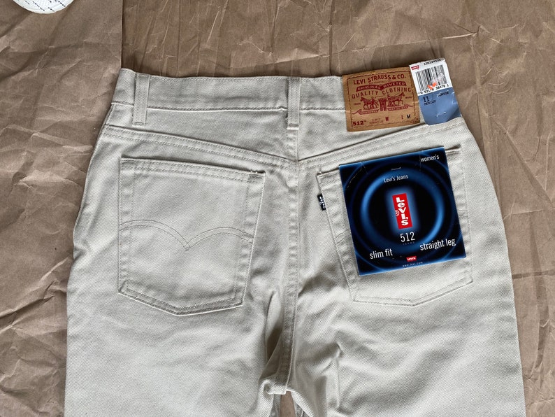 May include: A pair of light beige jeans with a back pocket and a Levi's tag. The tag says "Levi's Jeans" and "512 slim fit straight leg".