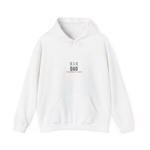 Puede incluir: Una sudadera blanca de manga larga con capucha, bolsillo tipo canguro frontal y un estampado gráfico centrado. El texto dice 614 DAD COLUMBUS, OHIO en letras negras y rojas con una línea horizontal que separa los números de la palabra DAD.
