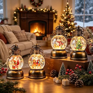 Könnte beinhalten: Vier antike Bronzelaternen mit Glaskugeln, die beleuchtete Weihnachtsszenen enthalten. Zwei Laternen zeigen den Weihnachtsmann, eine einen Schneemann und eine einen geschmückten Tannenbaum. Jede Laterne hat einen Metallsockel und einen Griff.