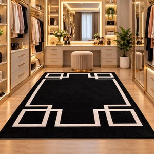 Puede incluir: Una alfombra rectangular que presenta un centro negro sólido y un borde geométrico blanco llamativo. El diseño consiste en líneas blancas interconectadas que forman formas cuadradas y rectangulares a lo largo del perímetro del campo negro.