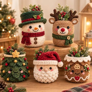 May include: Five crocheted holiday containers featuring a snowman with a green hat, a reindeer with antlers, a decorated Christmas tree, a Santa Claus with a red hat, and a gingerbread house, all filled with artificial pine and red berries.