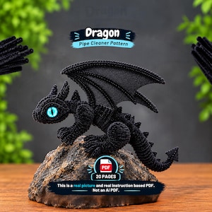 Könnte beinhalten: Eine schwarze Drachenfigur aus Pfeifenreinigern mit leuchtend blauen Augen, die auf einem strukturierten Felsen sitzt. Der Text lautet: Dragon Pipe Cleaner Pattern, PDF 20 PAGES, This is a real picture and real instruction based PDF. Not an AI PDF.