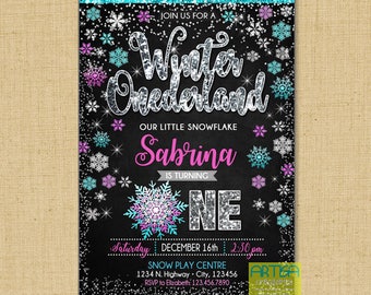 May include: A blue and silver glitter chalkboard style invitation for a first birthday party. The invitation says "Join us for a Winter Onederland. Our little snowflake Sabrina is turning one. Saturday, December 16th, 2:30 pm. Snow Play Centre, 1234 N. Highway, City, 123456. RSVP to Elizabeth: 123.456.7890."