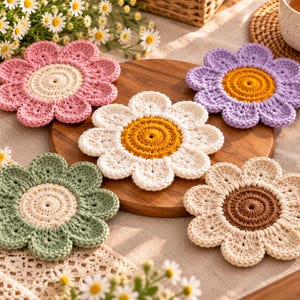 May include: A set of five round, flower-shaped crochet coasters. Each coaster features a central circular core in yellow, brown, or cream, surrounded by eight rounded petals in pink, purple, white, green, or cream yarn textures.