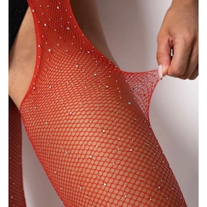 Può includere: Calze a rete rosso brillante con un motivo a maglia fine impreziosito da piccoli strass trasparenti e scintillanti sparsi sulla superficie. Il materiale è elastico e flessibile, consentendo al tessuto di essere tirato ed esteso.