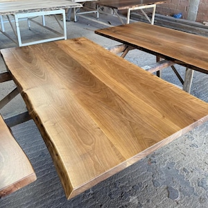 Könnte beinhalten: Eine rechteckige Tischplatte aus Holz mit Baumkante, die eine glatte, polierte Oberfläche mit sichtbarer natürlicher Holzmaserung in hellen und mittleren Brauntönen aufweist. Die Kanten bewahren die organische Form des Baumstammes.