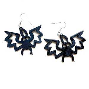 May include: A pair of black wooden bat earrings. The bats have a detailed design with wings and a body.