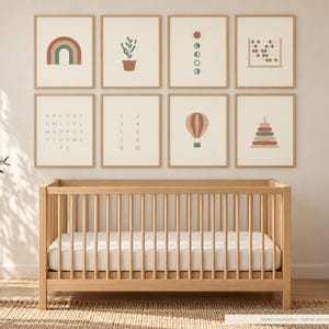 May include: A set of eight wall art prints featuring illustrations of a rainbow, a potted plant, moon phases, an abacus, the alphabet, numbers one through ten, a hot air balloon, and a stacking toy, displayed in light wood frames.