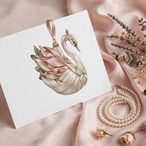 May include: A white greeting card featuring a central illustration of a swan ornament. The swan is crafted with cream and soft pink ribbon layers, accented with small white pearls and a pink ribbon loop at the top for hanging.