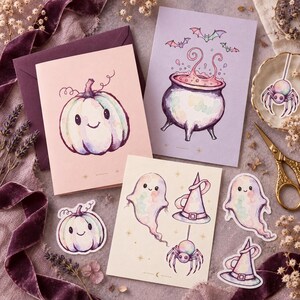 May include: A collection of stationery featuring watercolor illustrations of a smiling pumpkin, a bubbling cauldron with bats, and ghosts with witch hats and spiders. The set includes greeting cards, die-cut stickers, and envelopes.