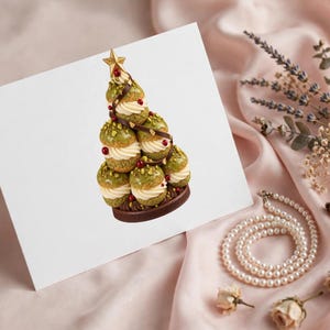 May include: A white greeting card featuring a printed image of a croquembouche shaped like a Christmas tree. The pastry tower is made of green glazed cream puffs, filled with white cream, decorated with red berries, and topped with a gold star.