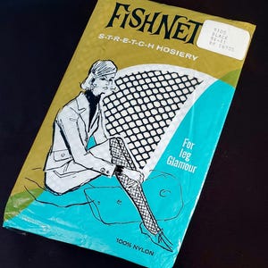 May include: A package of vintage Fishnet stretch hosiery. The packaging is gold and teal with a black and white illustration of a woman wearing fishnet stockings. Text on the package reads "For leg Glamour" and "100% Nylon."