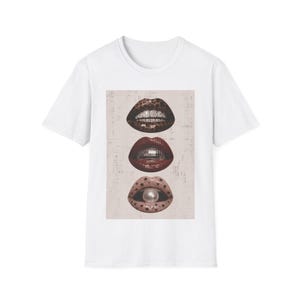 Può includere: Una t-shirt bianca a maniche corte con una stampa grafica centrale di tre paia di labbra impilate verticalmente. Le labbra superiori hanno una stampa leopardata con denti simili a diamanti, le labbra centrali sono rosse con una palla da discoteca e le labbra inferiori sono beige con stelle e una perla.