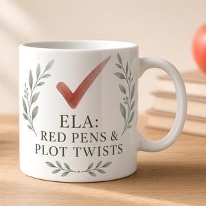 May include: A white ceramic mug featuring a watercolor red checkmark above the dark green text ELA: RED PENS & PLOT TWISTS. The design is framed by two vertical watercolor green leafy branches on either side and a small leafy sprig at the base.
