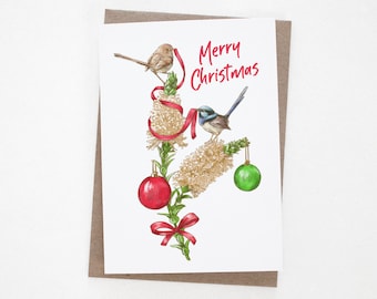 May include: A Christmas card featuring a watercolor illustration of two birds perched on a branch decorated with red and green ornaments. The text "Merry Christmas" is written in red lettering.