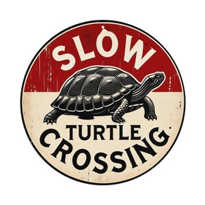 Könnte beinhalten: Ein rundes Metallschild mit abgenutzter Oberfläche und einer schwarzen Schildkrötenillustration in der Mitte. Die obere Hälfte ist rot mit dem weißen Text SLOW, die untere Hälfte ist cremefarben mit dem schwarzen Text TURTLE CROSSING.