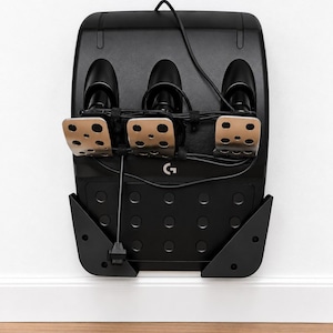 May include: A black gaming pedal set featuring three metallic pedals with circular cutouts, a textured base with a circular pattern, and a central Logitech G logo. A black cable is wrapped around the pedal stems and connected to the unit.