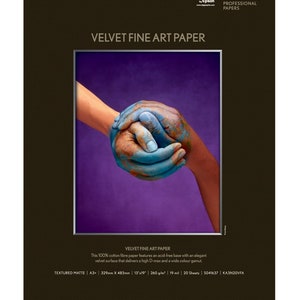 May include: Epson Velvet Fine Art Paper. The image shows a close-up of two hands, one painted blue and the other orange, clasped together against a purple background. The paper is textured matte, 13" x 19".