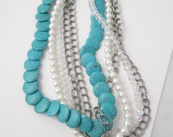 Hermoso collar de 5 hilos con cristales de turquesa sintética, perlas sintéticas y cadena de plata de doble eslabón.