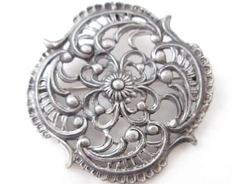 Broche grande de metal calado con filigrana color peltre, 5 cm de ancho.