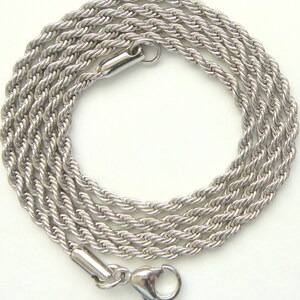 May include: A silver-colored rope chain necklace with a lobster clasp closure. The chain is made of tightly twisted strands, creating a textured, rope-like appearance. The necklace is displayed on a white background.