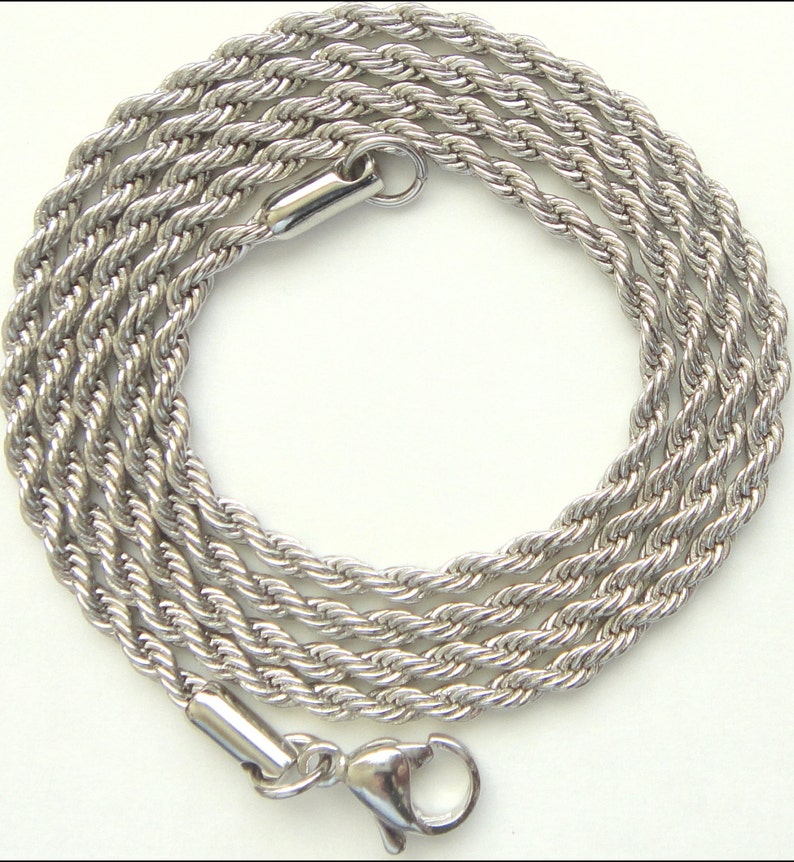 May include: A silver-colored rope chain necklace with a lobster clasp closure. The chain is made of tightly twisted strands, creating a textured, rope-like appearance. The necklace is displayed on a white background.