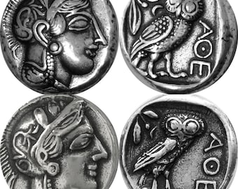 May include: Four silver coins. Two coins depict a woman's profile, and the other two feature an owl with the Greek letters AOE. The coins have a detailed, antique appearance, with visible textures and relief.