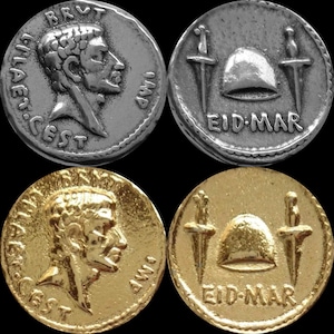 May include: Two sets of ancient Roman coins. The first set is silver and the second set is gold. Both sets feature a portrait of a man on one side and a helmet with two swords on the other side. The text on the coins reads "BRVT. IMP. CAESAR. CEST" and "EID. MAR".