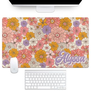 May include: A floral mousepad with a retro design. The pad features a pattern of pink, orange, yellow, and purple flowers on a cream background. The name "Alyssa" is written in a cursive font. A white mouse and keyboard are also visible.