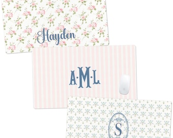 May include: Three rectangular mouse pads with decorative designs. One pad features a floral pattern with the name "Hayden" in blue script. Another has pink and white stripes with the initials "A.M.L." in blue. The third pad has a blue and white floral pattern with the letter "S".