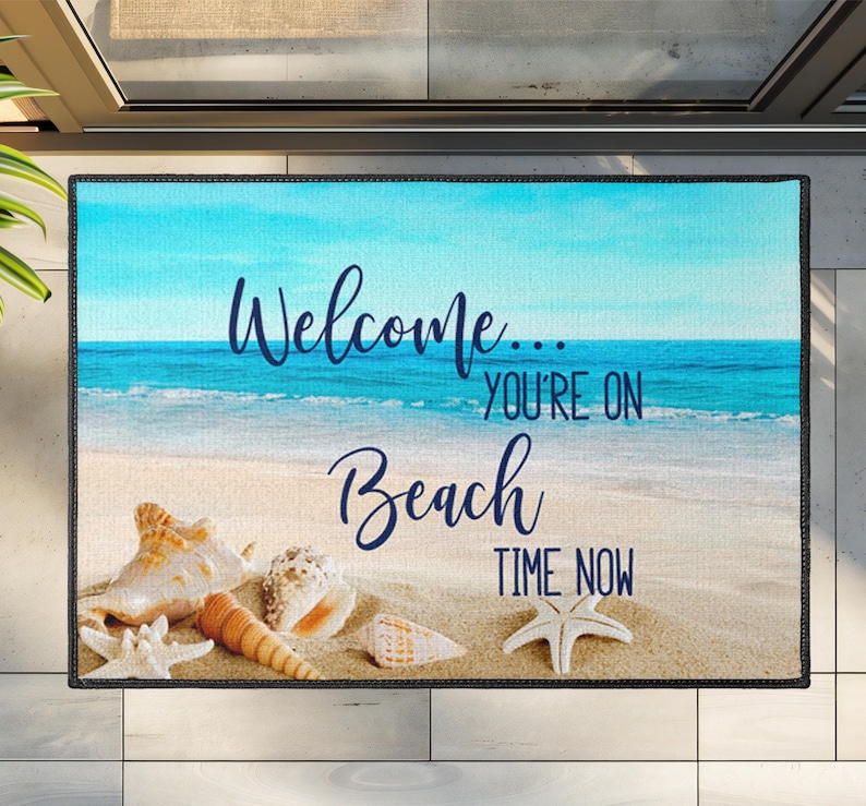 image of a beach entrance rug with 'welcome' you're on beach time now, the beautiful relaxing beach background features a vibrant tranquil beach scene adorned with seashells and starfish, perfectly capturing the relaxed, coastal vibe.
