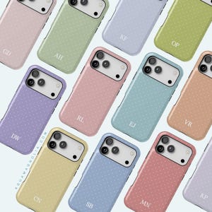 May include: A collection of pastel-colored phone cases with a polka dot pattern. Each case has a different color and a white camera module. The cases are personalized with initials in a simple font. The cases are arranged on a light background.