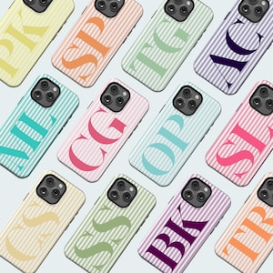 May include: A collection of colorful phone cases with striped backgrounds and large, bold initials. The cases feature a variety of colors, including yellow, orange, green, blue, pink, and purple. Each case has a different initial in a contrasting color.