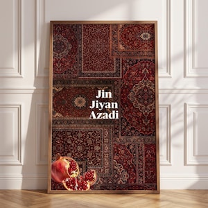 May include: A rectangular framed wall art piece featuring a collage of deep red Persian-style rug patterns. The text Jin Jiyan Azadi is printed in white in the center. A sliced pomegranate with visible red seeds is positioned at the bottom left corner.