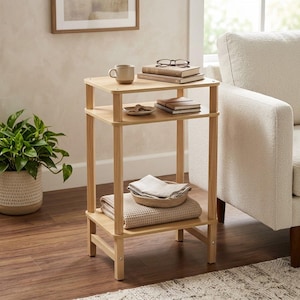 May include: A light-toned wooden side table with three rectangular tiers. The top tier holds a ceramic mug, a stack of books, and eyeglasses. The middle tier features a small dish. The bottom tier contains a folded textile and a woven bowl.
