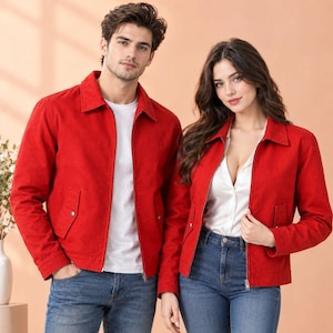 May include: Two individuals wearing matching bright red zip-up jackets with pointed collars and front pockets. The jackets are worn over simple shirts and blue denim jeans, creating a coordinated look with clean lines and silver hardware.