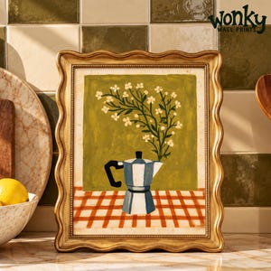 Puede incluir: Una lámina enmarcada con la pintura de una cafetera moka azul y blanca sobre un mantel de cuadros rojos y blancos, con un fondo verde y flores blancas. El marco es dorado con un borde ondulado. El texto "wonky WALL PRINTS" es visible.