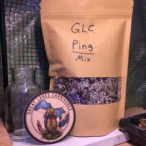 May include: A tan stand-up pouch containing a soil mix, labeled G.L.C. Ping. Mix in black marker. A circular sticker features a pitcher plant illustration and the text Great Lakes Carnivores. A clear glass jar sits to the left of the pouch.