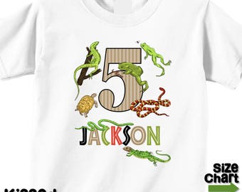 May include: White t-shirt with a brown number 5 surrounded by green and red snakes, a green lizard, a turtle, and a frog. The name "JACKSON" is written below the number.