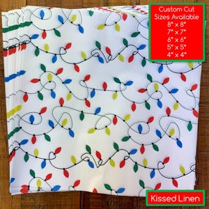 May include: White linen fabric with a repeating pattern of colorful Christmas lights. The lights are red, green, blue, and yellow. Text on the image reads "Custom Cut Sizes Available" with size options from 4" x 4" to 8" x 8". The text "Kissed Linen" is also visible.