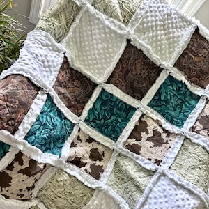 Może przedstawiać: Kołdra patchworkowa z różnymi wzorami i kolorami, w tym białym, brązowym, turkusowym i zielonym. Kołdra jest wykonana z miękkiej, puszystej tkaniny i ma falbankę.