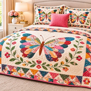 May include: A cream-colored quilt featuring a large central butterfly with multicolored patterned wings, surrounded by a floral vine border. The quilt includes matching pillow shams with butterfly motifs and a solid pink accent pillow.