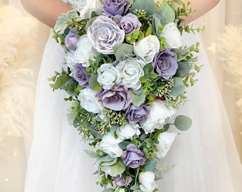 Pode incluir: Um buquê de noiva em cascata com rosas brancas e lavanda, folhagem e eucalipto.