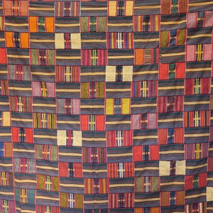 May include: A woven textile fabric featuring a repeating grid pattern of dark blue horizontal stripes interspersed with rectangular blocks in shades of red, yellow, green, and cream, creating a multi-colored geometric design across the entire surface.