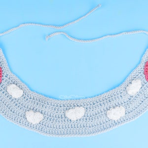 Pu&ograve; includere: Un cerchietto in crochet blu chiaro con due motivi arcobaleno e nuvole. Il cerchietto ha una chiusura a nodo.