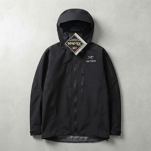 Op de afbeelding: Een zwarte Arc'teryx jas met capuchon, voorzien van een volledige ritssluiting aan de voorzijde, twee verticale borstzakken met rits en een wit geborduurd logo op de linkerborst. Een ruitvormig Gore-Tex label is aan de kraag bevestigd.