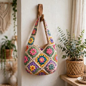 Peut inclure: Un sac fourre-tout en crochet composé de carrés granny multicolores avec des motifs floraux dans des tons de rose, jaune, violet, bleu sarcelle et vert, assemblés avec du fil couleur crème, suspendu à un crochet en bois sur un mur.