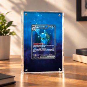 Può includere: Una cornice magnetica in acrilico trasparente contenente una carta collezionabile Blastoise ex. La carta raffigura una tartaruga blu, 330 HP e il testo Solid Shell e Twin Cannons. La cornice presenta uno sfondo con design subacqueo blu.
