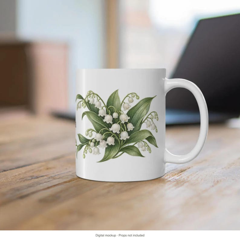 May include: A white ceramic mug featuring a botanical illustration of lily of the valley flowers with small white bell-shaped blossoms and green leaves centered on the front. The mug has a smooth finish and a curved handle on the right side.