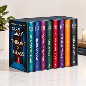 May include: A complete book collection box set titled Throne of Glass by Sarah J. Maas. The set includes eight hardcover books with colorful spines in teal, blue, purple, green, red, violet, orange, and black, each featuring gold text and symbols.